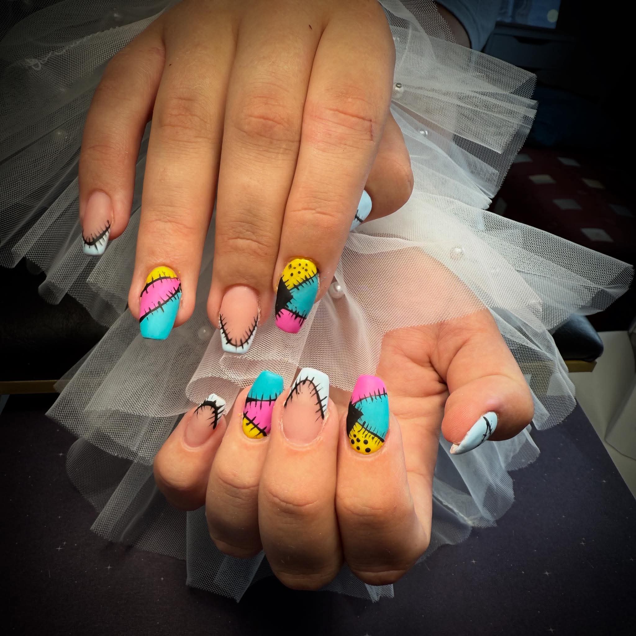 Patchwork nail art in felle kleuren met zwarte steekjes